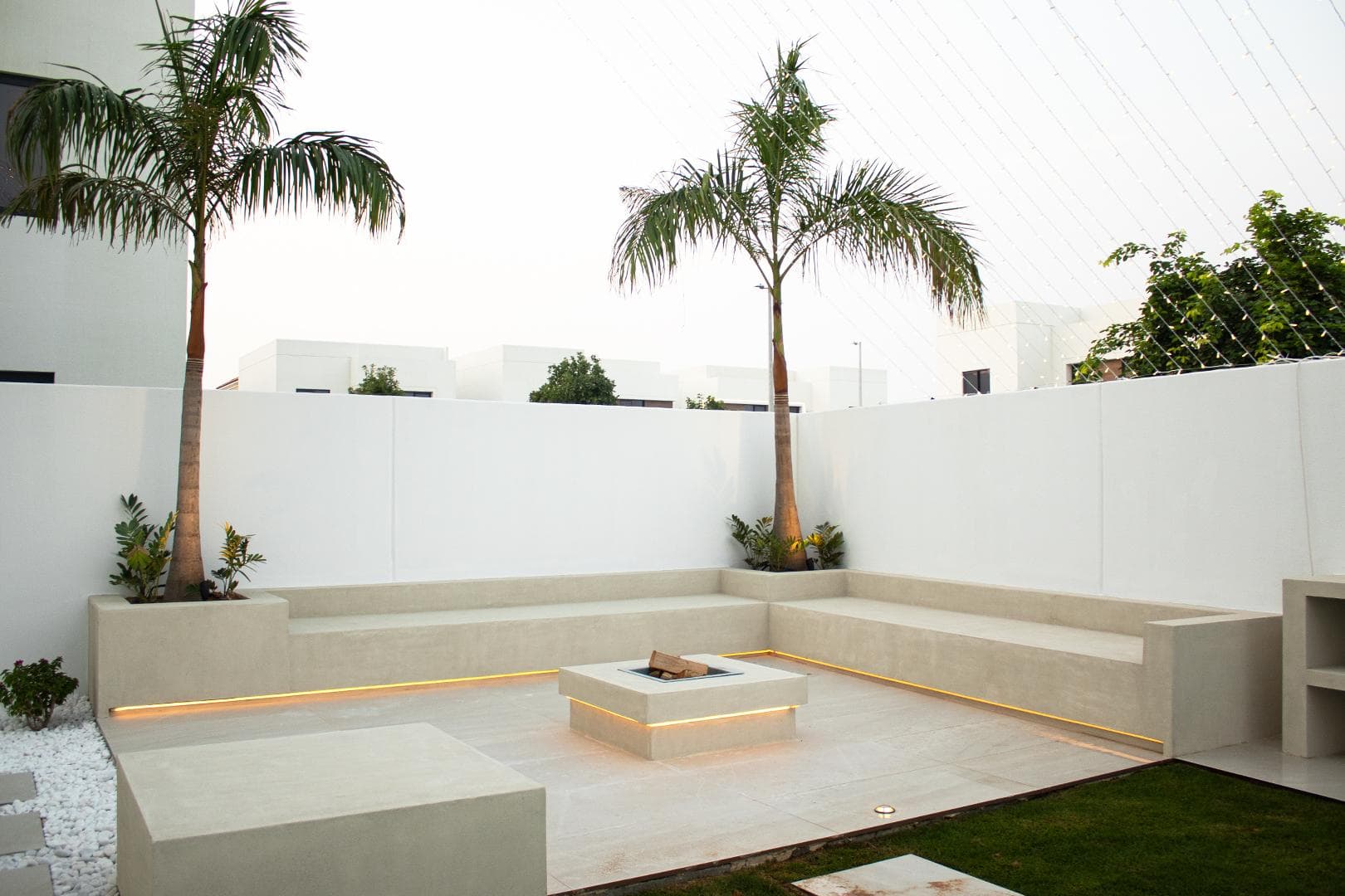 Sunken concrete lounge with fire pit and palm planting at a private villa