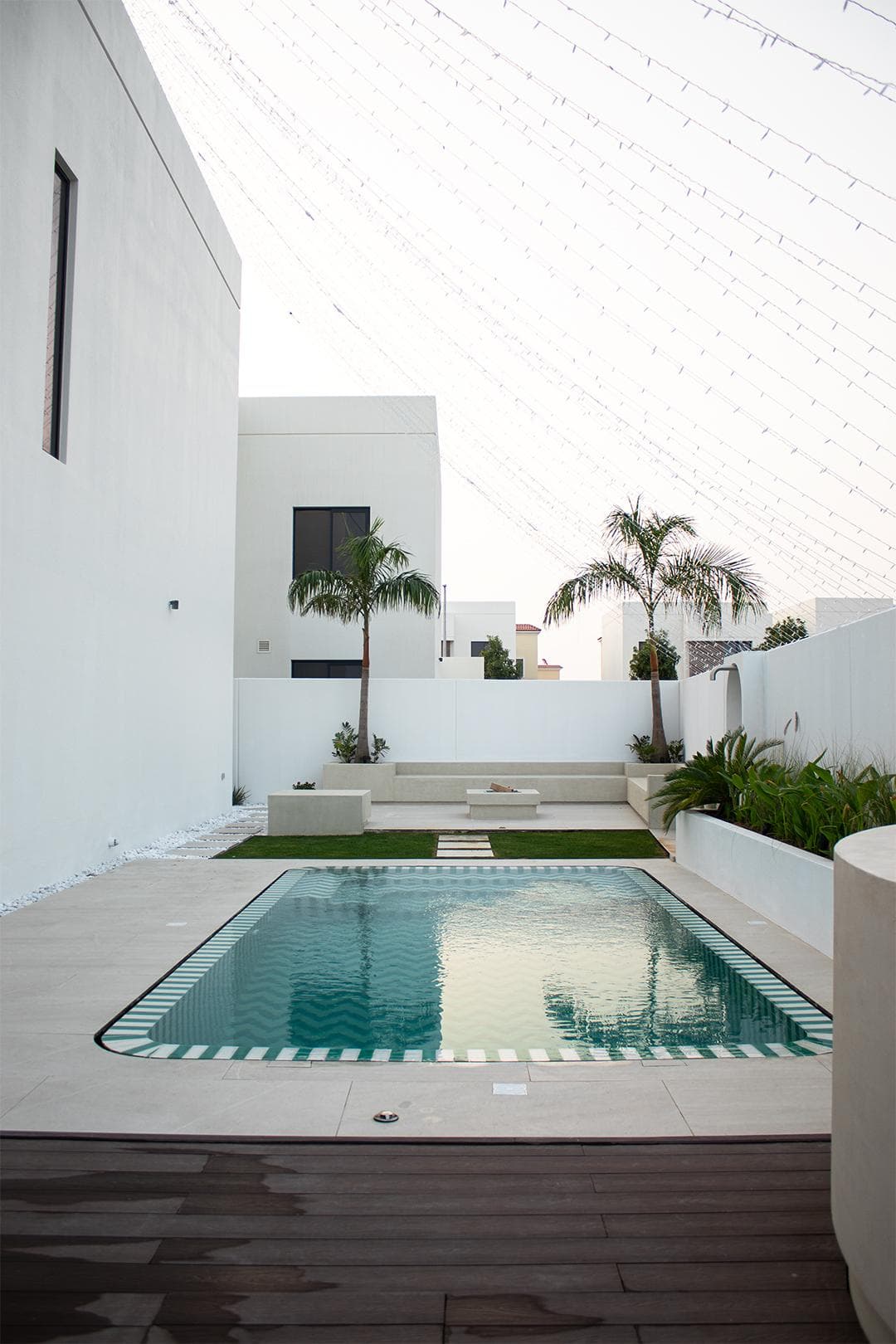 Villa courtyard pool with palm trees and layered planting at dusk