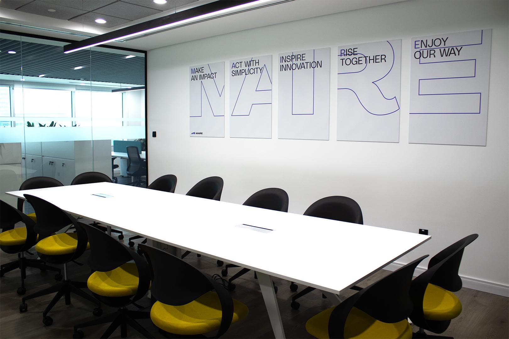 Maire boardroom with poster wall, conference table and yellow task chairs