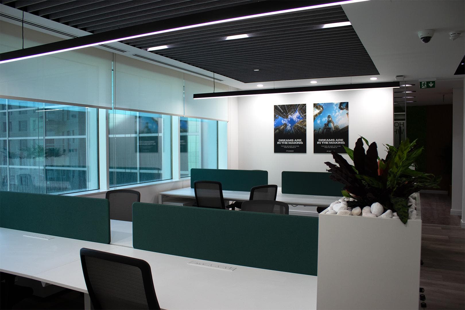 Office ceiling with acoustic baffles, linear lighting and dome CCTV camera