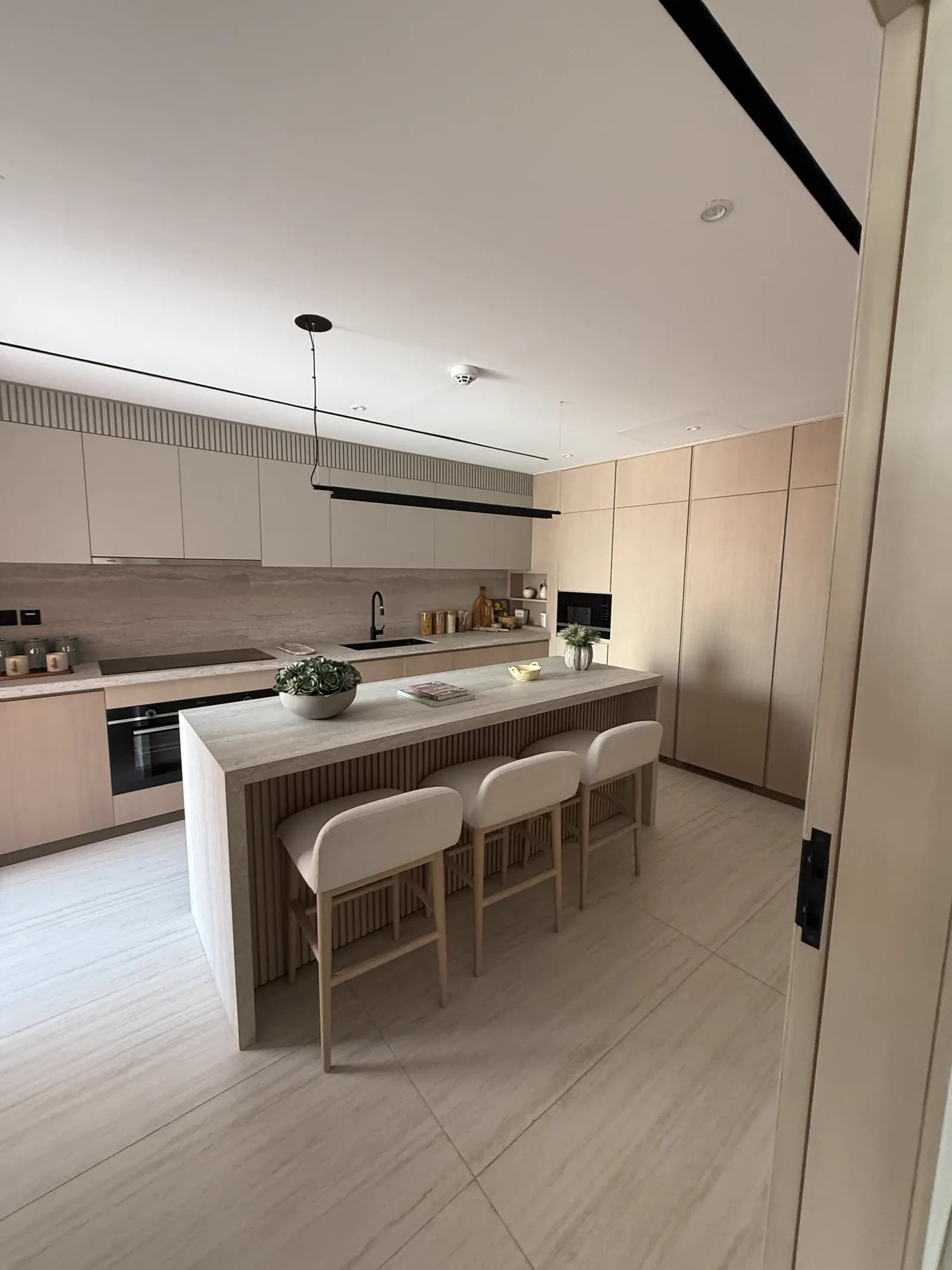 Kitchen with a breakfast bar, integrated appliances and pendant lighting