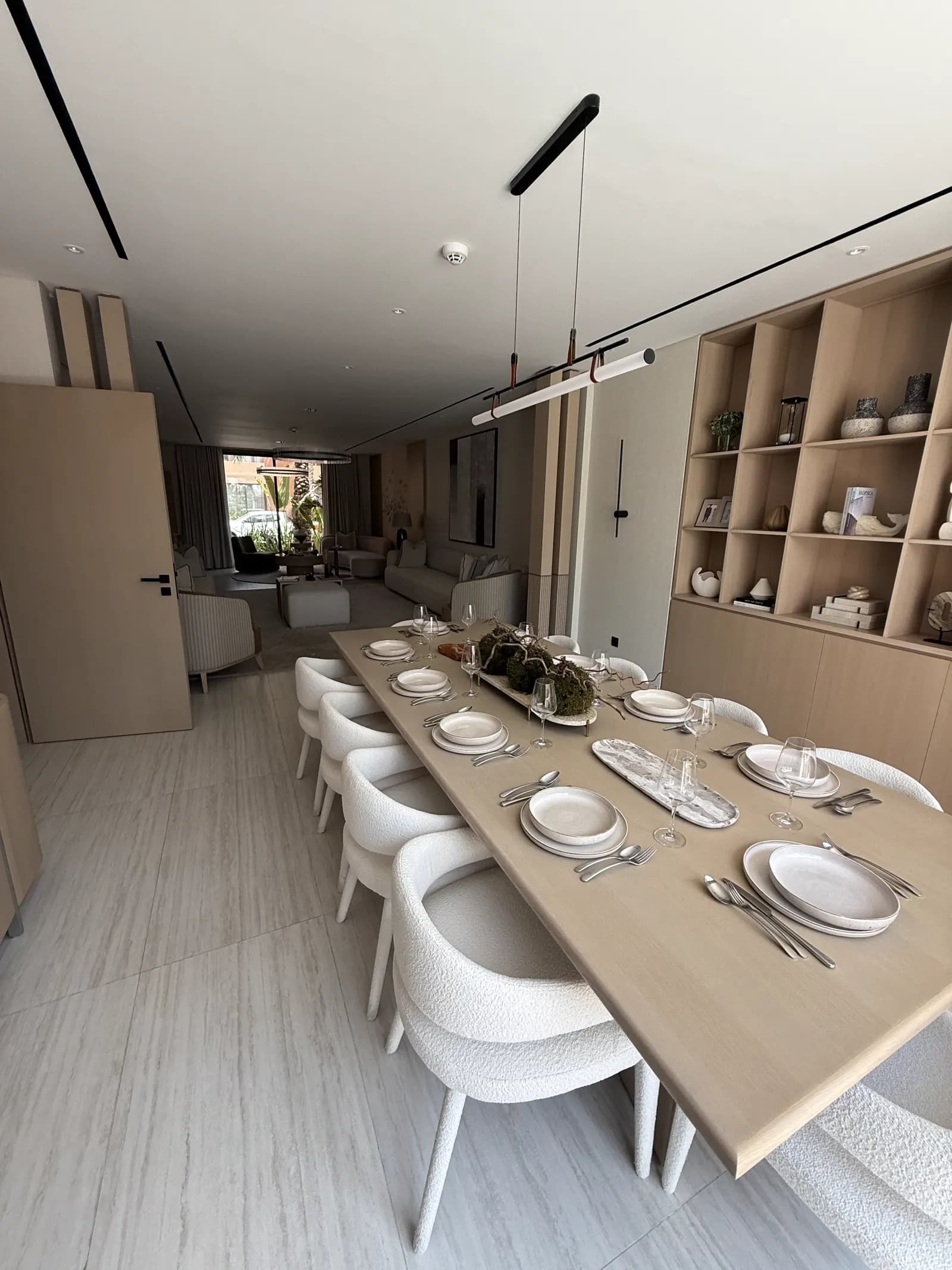 Dining room with a long table, display joinery and full-height curtains