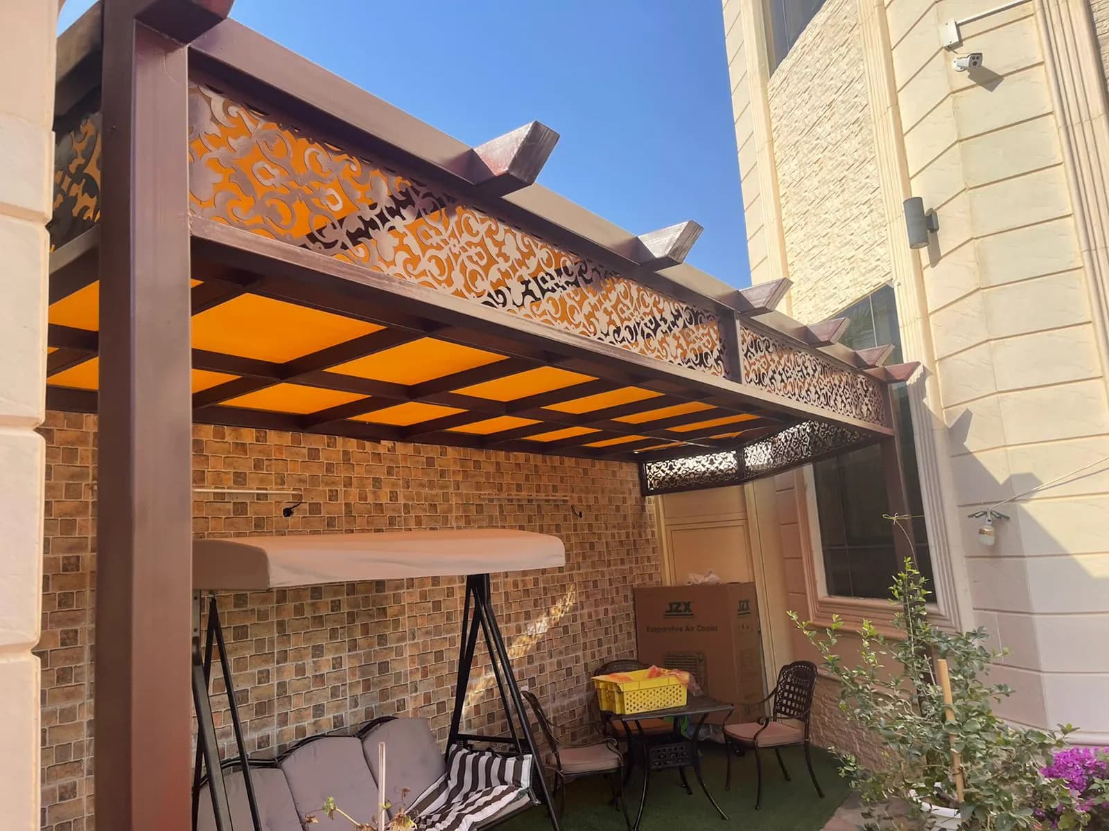 Covered outdoor lounge with a swing seat, patterned tile wall and garden furniture