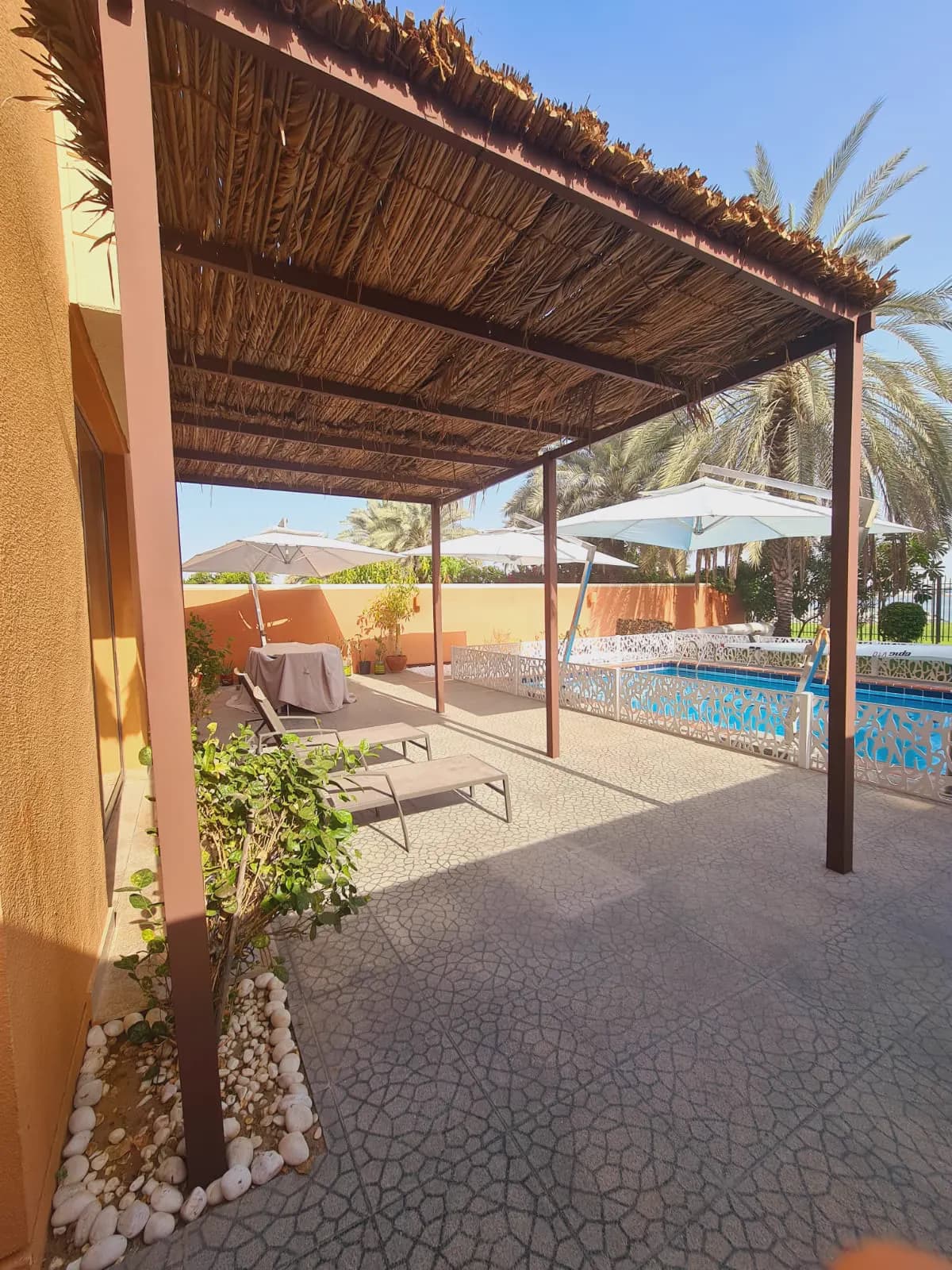 Pergola-shaded poolside terrace with loungers, parasols and climbing planting