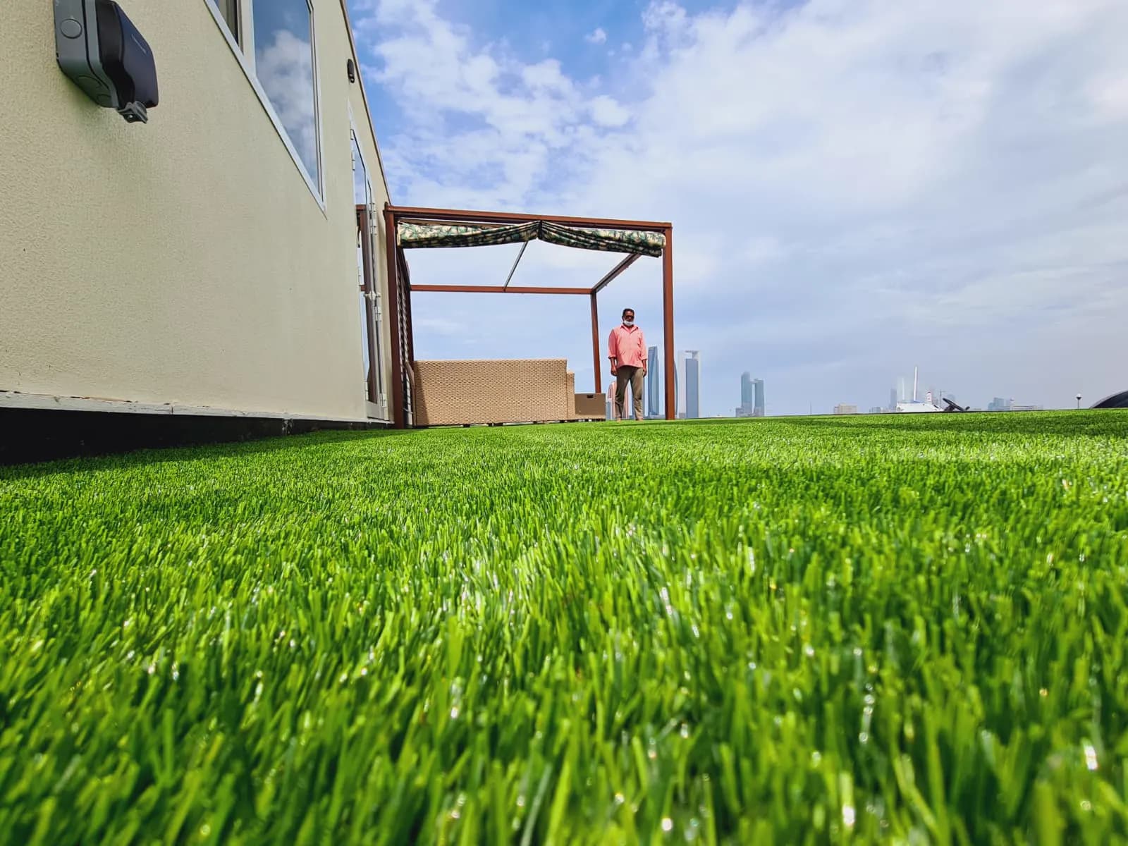 Manicured lawn with a shade structure and the Abu Dhabi skyline beyond