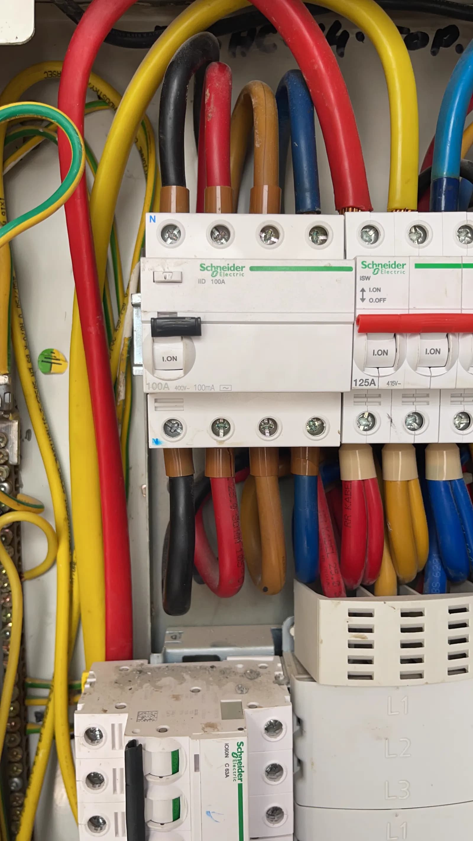 Schneider circuit breakers and colour-coded distribution cabling inside an electrical panel
