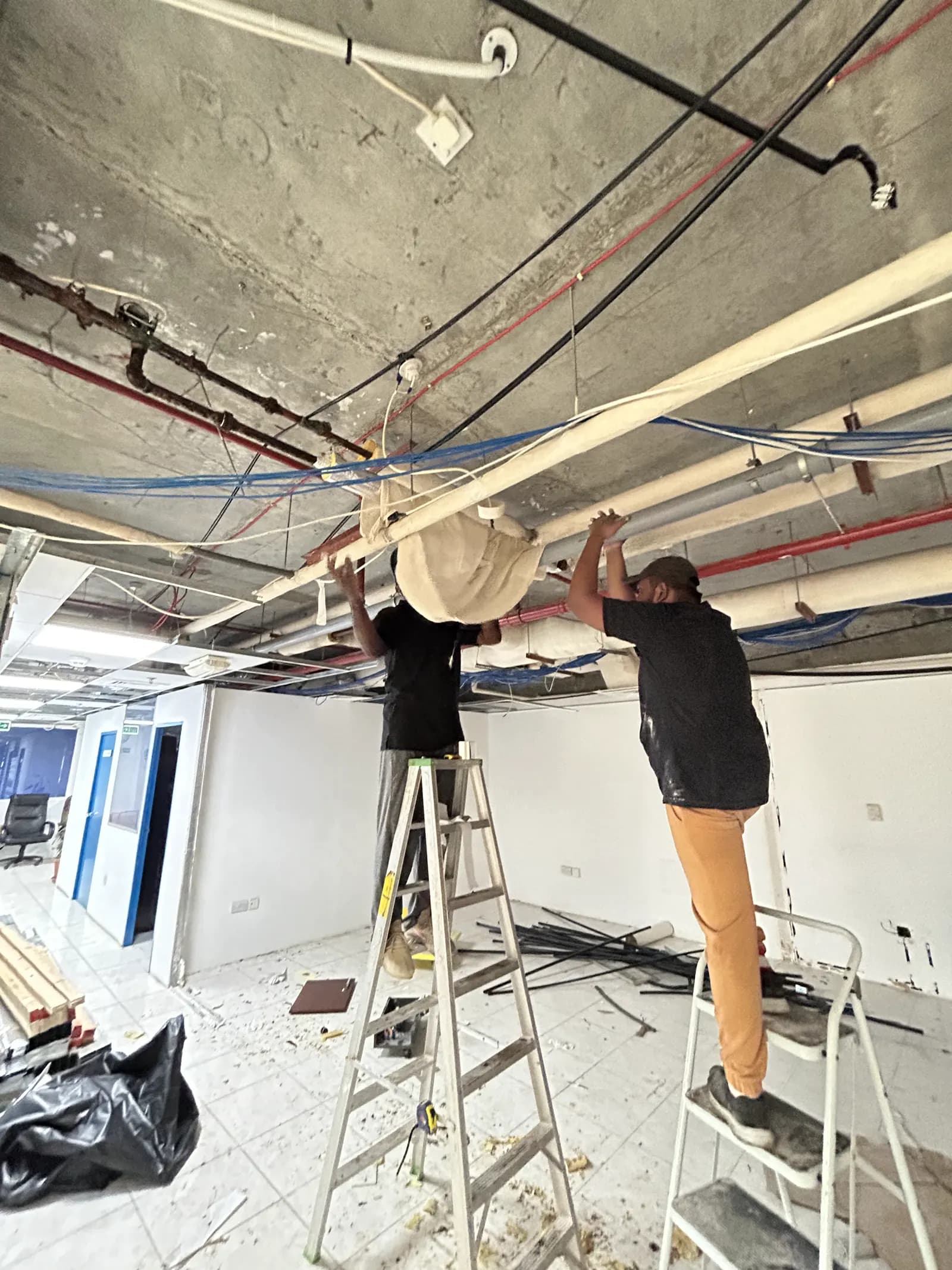 Technicians installing ceiling services before the suspended ceiling is closed