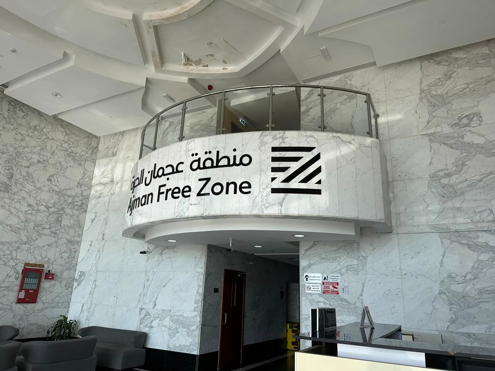Ajman Free Zone reception with curved marble desk surround and branded signage