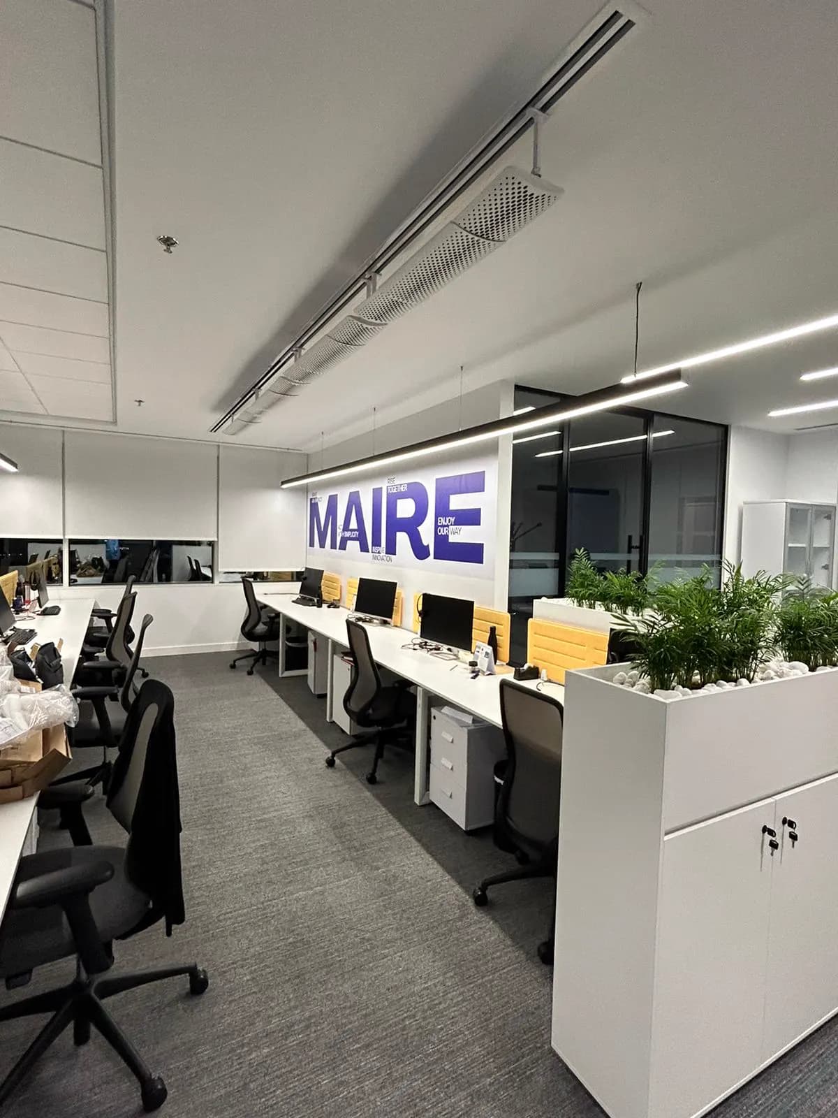 Maire Tecnimont open-plan workstations with planted dividers and brand wall