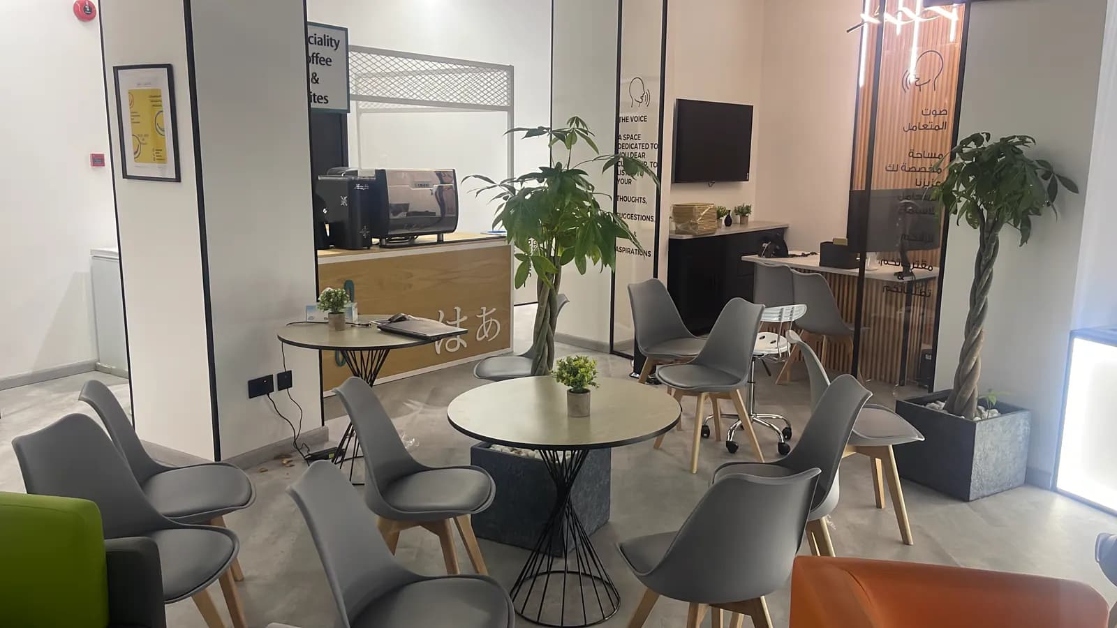 Office breakout area with round tables, mixed seating and a planted screen