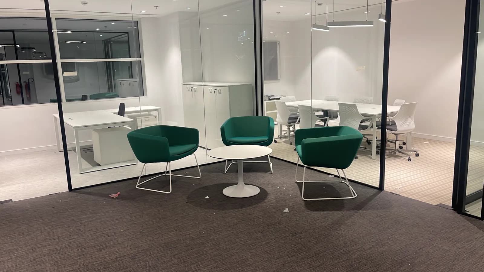 Meeting lounge with teal armchairs, glass partitions and acoustic ceiling