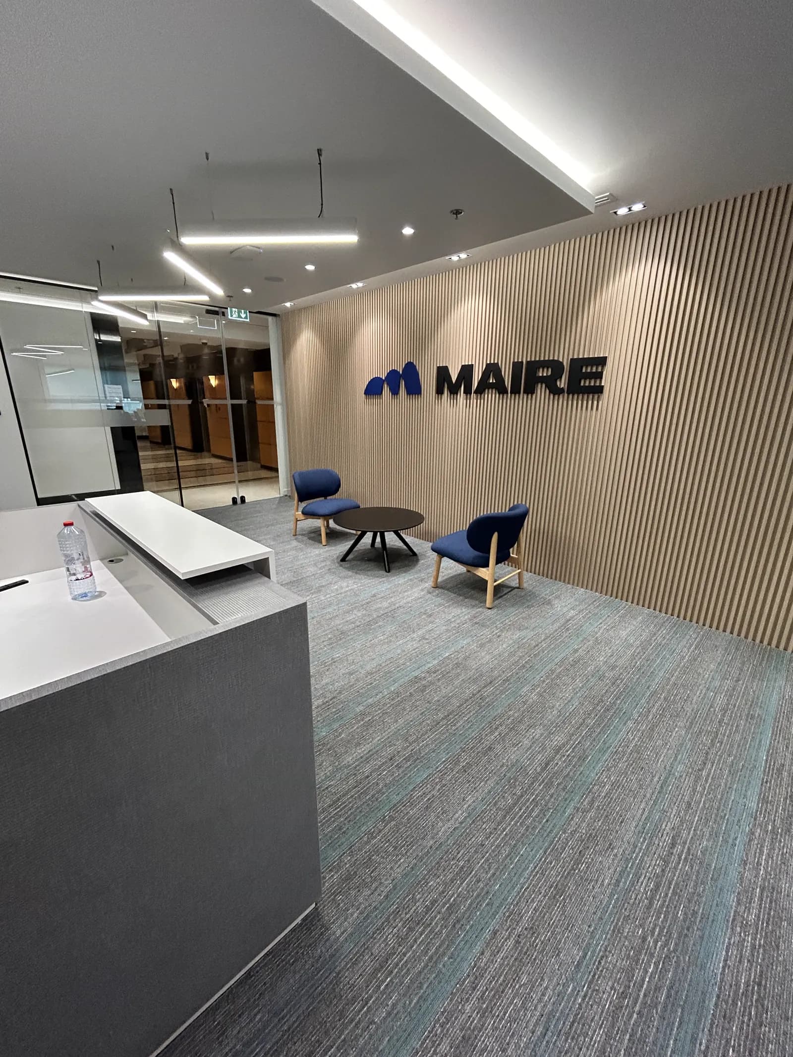 Maire Tecnimont reception desk and lounge seating under a timber slat feature wall