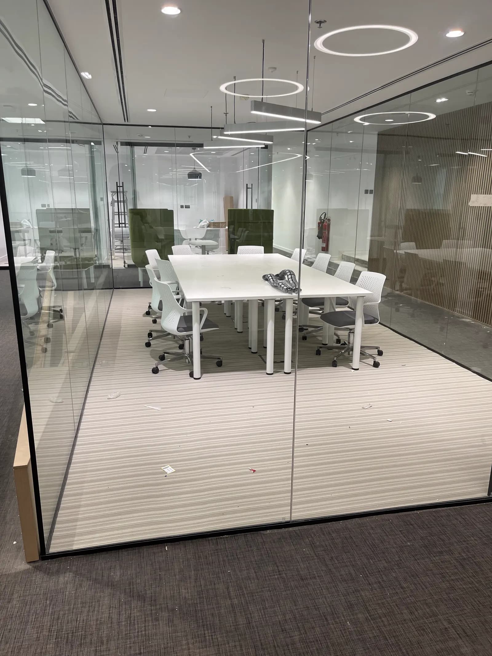 Glass-partitioned boardroom with a white conference table and mesh seating