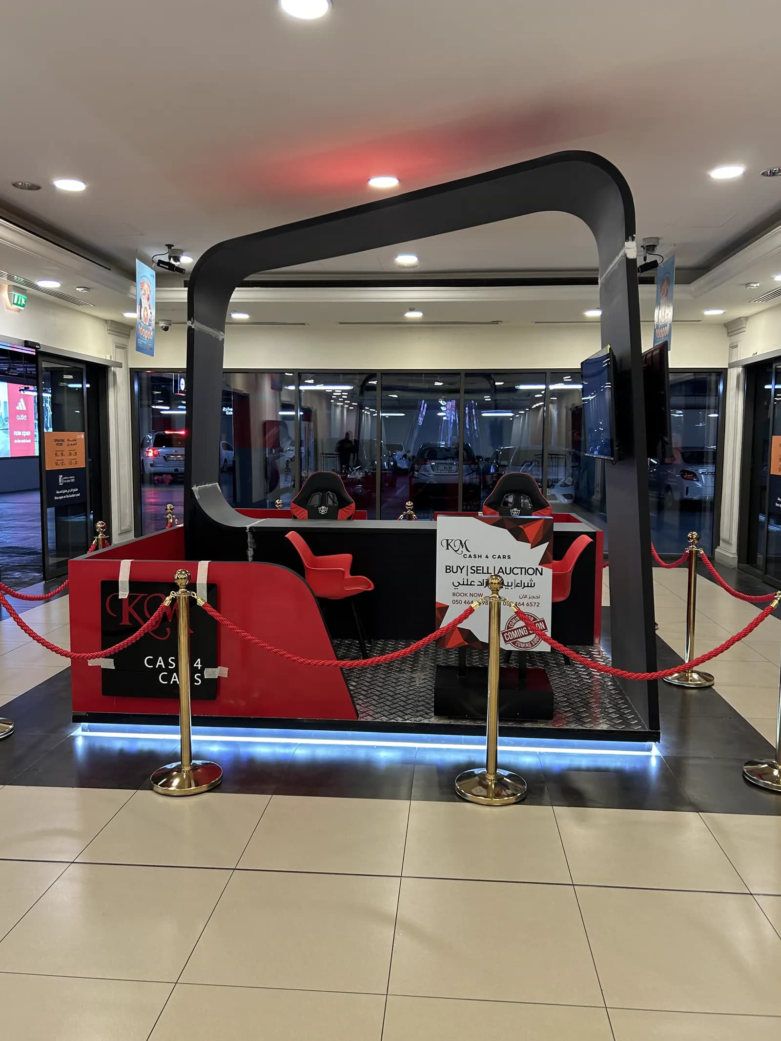 Mall retail kiosk with illuminated plinth, brand arch and rope barriers